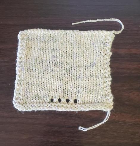 White swatch with flecks of green and lavender, wet blocked