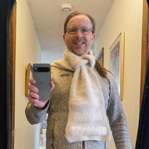 One last selfie with the scarf, this time knotted in a couple of loops around itself below the chin. A bit of pony tail is sticking out to the side, while the photographer gives a bit of a smile.