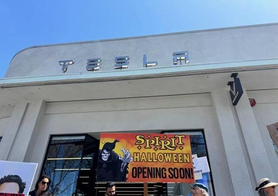 a "Spirit Halloween" sign in front of the Tesla showroom