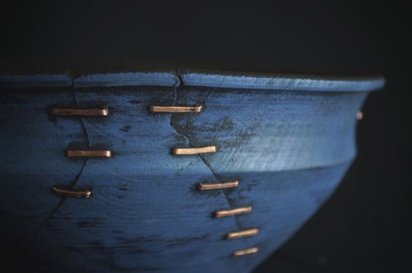 detail photo of a light blue repaired bowl. The bowl has been repaired using copper.